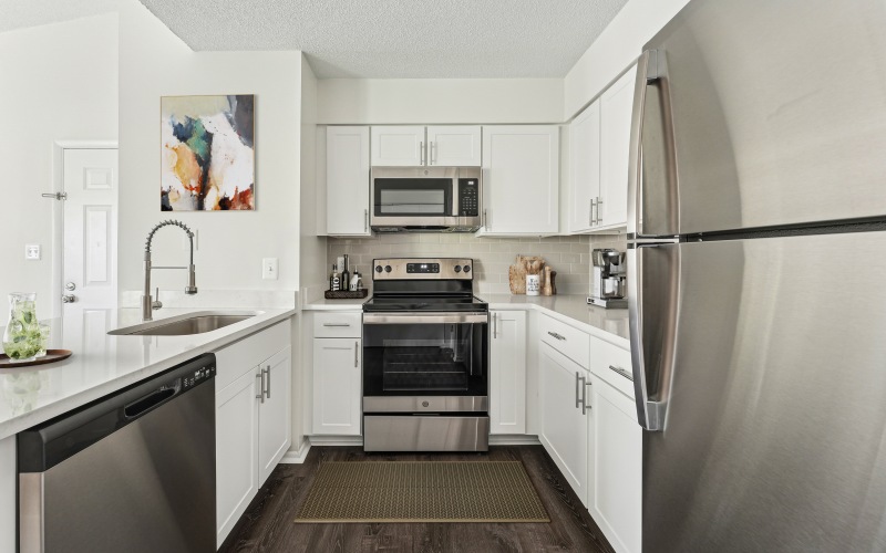 Kitchen with tile backsplash, stainless steel appliances,  and vinyl plank flooring