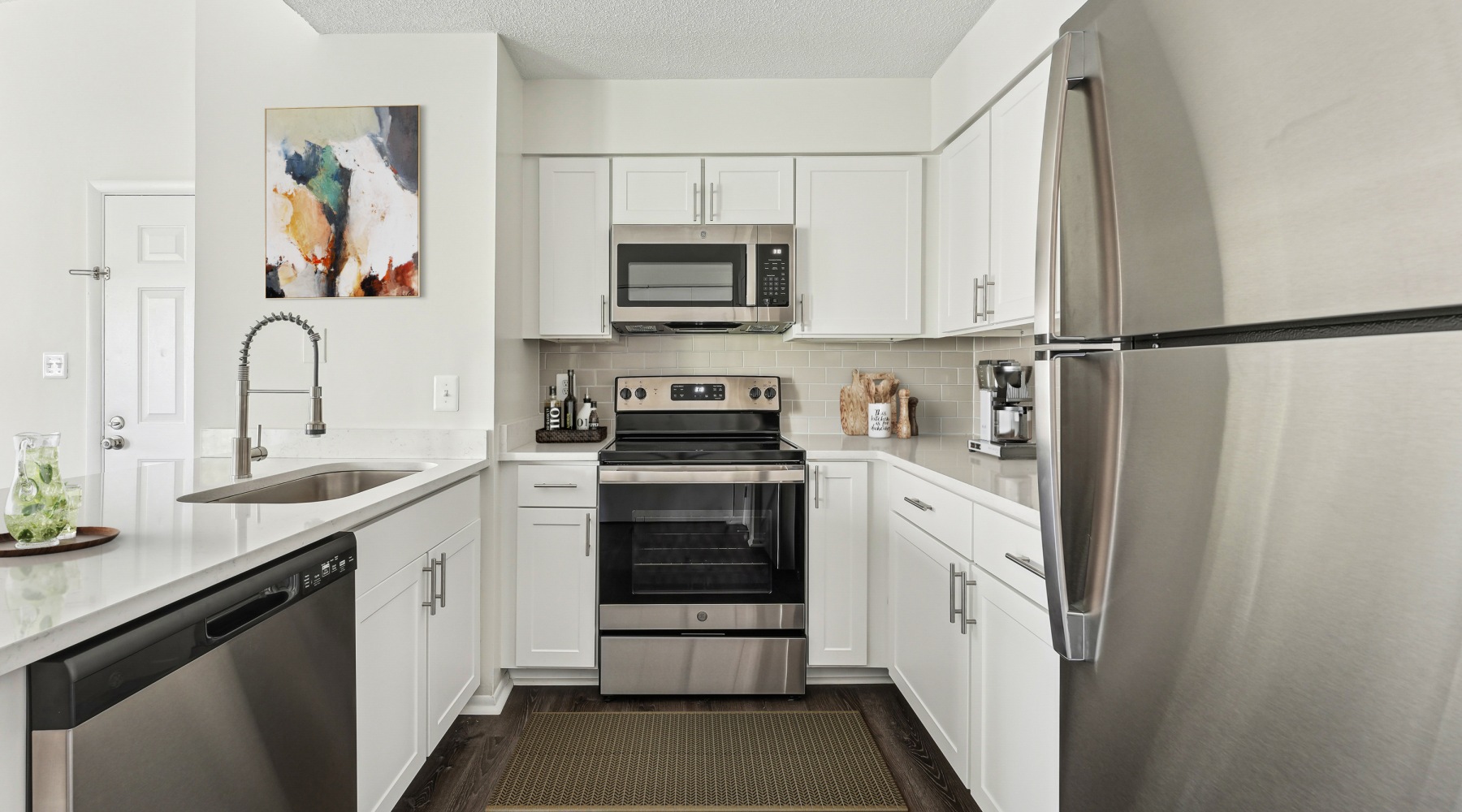Kitchen with tile backsplash, stainless steel appliances,  and vinyl plank flooring Kitchen with tile backsplash, stainless steel appliances,  and vinyl plank flooring